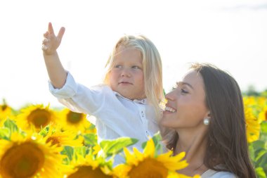 Bir anne, parlak ve güneşli bir günde çocuğuna sarılır ve ayçiçekleriyle dolu bir tarlayı keşfeder. Çocuk şakacı hareketler yapar ve her ikisi de doğanın güzelliğinde neşeli bir anı paylaşır..