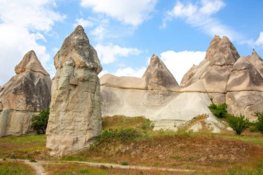 Türkiye 'nin Kapadokya kentindeki mavi gökyüzüne karşı heybetli kaya oluşumları yükseliyor.