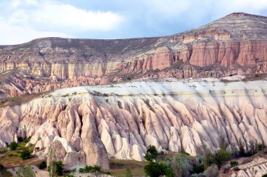 Türkiye 'nin Kapadokya kentindeki görkemli kaya oluşumları bulutlu bir gökyüzünün altındaki renkli yeryüzü katmanlarını ortaya çıkarıyor..
