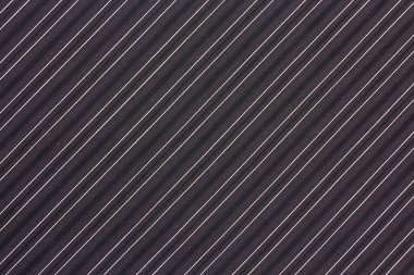 Kumaş, köşegen çizgilerle süslenmiş karmaşık bir koyu arkaplana sahiptir..