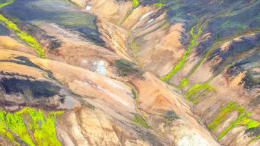 İzlanda 'daki canlı jeolojik oluşumlar toprak ve parlak yeşilliğin karışımını ortaya çıkarıyor. Dramatik manzara engebeli araziyi ve volkanik aktiviteyi gösteren renkli desenleri gösteriyor..