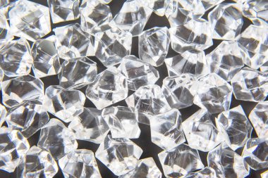 Parlak kristaller karanlık bir yüzeye dağılmış, ışığı güzel yansıtıyor, lüks ve zarafet temalı tasarımlar veya şenlikli dekorasyonlar için mükemmel..