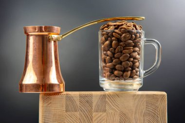 Parlak bakır bir Türk kahve makinesinin yakın çekimi ve ahşap bir bloğa konmuş kahve çekirdekleri taşan şeffaf bir fincan. Sıcak tonlu, zengin, aromatik bir kahve konsepti..