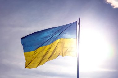 Ukrayna 'nın ulusal bayrağı güneş ve mavi gökyüzünün arka planına karşı. Vatanseverlik ve ulusal sembol