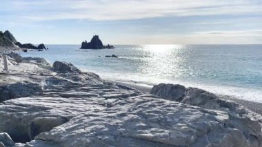 Liguria 'daki Asseu kayası ve denizi. Kayanın üstünde çapraz. Riva Trigoso dönüm noktası. Gündüz vakti güneşin suya yansıması. - Evet. Yüksek kalite 4k görüntü