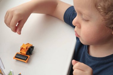 Beyaz masada arabasıyla oynayan kıvırcık saçlı sarışın çocuk. Çocuklar için geliştirme oyunları. - Evet. Yüksek kalite fotoğraf