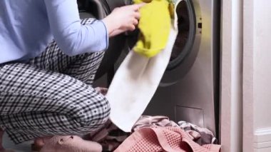 Pijamalı kadın kirli havlu ve yatağı açık çamaşır makinesine koyuyor. Temizlik ve daire düzenleme. Modern iç mekan ve yaşam tarzı. - Evet. Yüksek kalite 4k görüntü