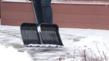 Kadın kışın arka bahçede kürekle kar temizliyor. Temiz ve düzenli. Mevsimler ve açık hava temizliği. - Evet. Yüksek kalite 4k görüntü