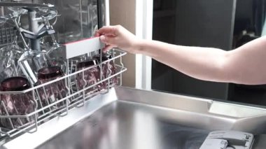 Kadınlar bulaşık makinesinden şarap bardaklarını çıkarıp boşaltıyorlar. Temiz ve düzenli. Bulaşıkları taşıyıcıya yerleştirmek, kirli eşyaları yüklemek. Yüksek kalite 4k görüntü