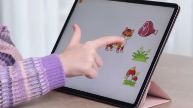 Kız tablette eğitim oyunuyla oynuyor. Okul öncesi gelişim ve teknoloji. Hayvanlar ve yiyecekler. - Evet. Yüksek kalite 4k görüntü