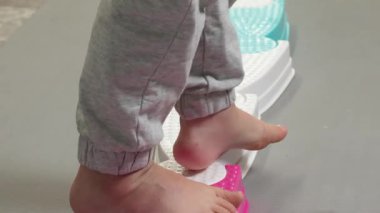 Çocuk odada plastik yolda yalınayak yürüyor. Ayak masajı. Sağlık ve spor, etkinlik. Büyük motor becerilerin gelişimi. Denge ve koordinasyon. - Evet. Yüksek kalite 4k görüntü