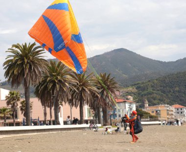 Sestri Levante, İtalya - 12 Nisan 2025. Paraglider deniz yoluyla sahile indi, paraşütü kontrol ediyordu. Spor ve sağlık. Doğa ve insan. Yaz ve tatil kavramı. Yüksek kalite fotoğraf