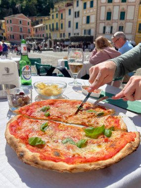 Portofino, İtalya - 07 Nisan 2025. İtalya 'da Aperitivo caddesinde. Becks birası. Yiyecek ve içecek. Adam Margherita pizzasını bıçakla kesti. - Evet. Yüksek kalite fotoğraf