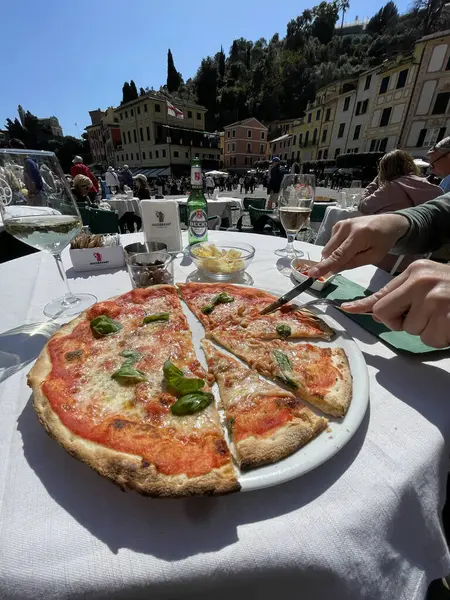 Portofino, İtalya - 07 Nisan 2025. İtalya 'da Aperitivo caddesinde. Becks birası. Yiyecek ve içecek. Adam Margherita pizzasını bıçakla kesti. - Evet. Yüksek kalite fotoğraf
