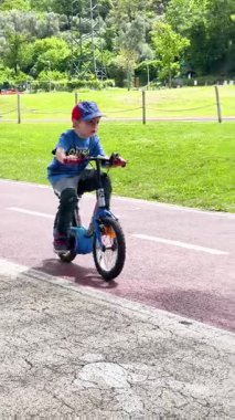 Sestri Levante, İtalya - 26 Nisan 2025. Küçük çocuk parkta bisiklet sürüyor. Spor ve sağlık. Yüksek kalite 4k görüntü