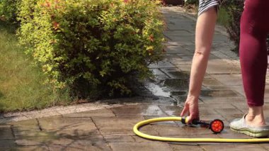 Minsk, Belarus - Haziran 04, 2025. Kadın hortumla hortumu alıp çalıları suluyor. Doğa ve bahçe işleri. Yaşam tarzı ve aletleri. - Evet. Yüksek kalite 4k görüntü