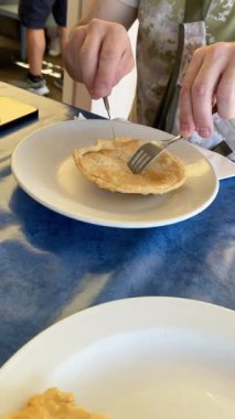 Adam Liguria, Recco 'da geleneksel İtalyan usulü kızarmış ekmeği tabakta peynirle kesiyor. Yemek ve otantik restoran. Yüksek kalite 4k görüntü