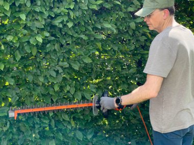 Çalıları elektrikli çit budayıcı ve testere ile buduyor. Bahçıvanlık ve temizlik. Doğa ve bahçe bakımı. Yüksek kalite fotoğraf