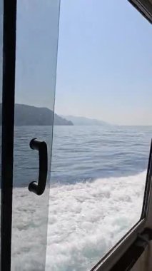 Cinque Terre, İtalya - 25 Haziran 2025. Akdeniz 'de dağ manzaralı yolcuları olan bir turist teknesi. Güncel ve hızlı. İtalya 'nın doğası, Cinque Terre. Yüksek kalite 4k görüntü