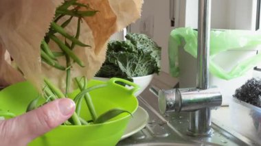 Kadın kevgire kese kağıdından yeşil fasulye döktü. Sağlıklı yiyecek ve sebzeler. Organik mevsimlik tarım ürünleri. Yüksek kalite 4k görüntü