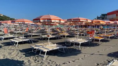 Sestri Levante, İtalya - 9 Ağustos 2025. Plaj şemsiyeleri ve deniz kenarında güneşlenme yerleri. Yaz, Liguria, İtalya 'da tatil. Metin için arka plan. Yüksek kalite 4k görüntü
