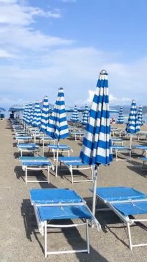 Plaj şemsiyeleri ve deniz kenarında güneşlenme yerleri. Yazın gün doğumu, İtalya, Liguria 'da tatil. Metin için arka plan. Yüksek kalite 4k görüntü