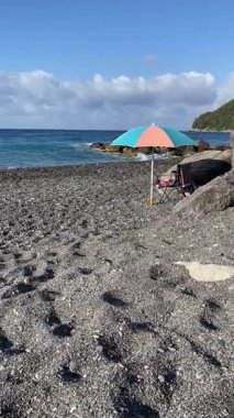Güneş şemsiyesi yazın vahşi sahilde. Kalabalık olmadan deniz kıyısında turizm ve eğlence. Ekolojik olarak temiz doğa. Yüksek kalite 4k görüntü