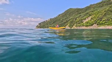 Dağın arka planına karşı denizde kürek çeken bir adam. Spor ve sağlık. Turizm ve eğlence, yaşam tarzı. Yüksek kalite 4k görüntü