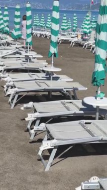 Sestri Levante, İtalya - 30 Ağustos 2025. Plaj şemsiyeleri ve deniz kenarında güneşlenme yerleri. Yaz, Liguria, İtalya 'da tatil. Metin için arka plan. - Evet. Yüksek kalite 4k görüntü