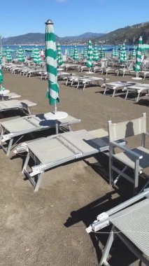 Sestri Levante, İtalya - 30 Ağustos 2025. Plaj şemsiyeleri ve deniz kenarında güneşlenme yerleri. Yaz, Liguria, İtalya 'da tatil. Metin için arka plan. - Evet. Yüksek kalite 4k görüntü
