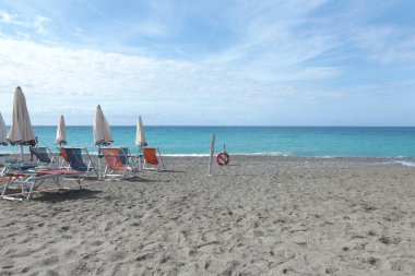 Deniz kıyısındaki Lacoste markasının plaj şemsiyeleri ve güneş şezlongları. Yaz, Liguria, İtalya 'da tatil. Metin için arka plan. Yüksek kalite fotoğraf