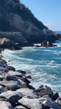 Yazın güneşli havalarda dalgalar ve deniz taştan dalgalarla kaplıdır. Mavi deniz ve dağlar. Liguria 'da turizm sezonu. Yüksek kalite 4k görüntü