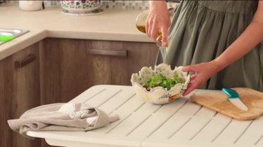 Kadın marul yapraklarının üzerine eski seramik kasede desenli zeytin yağı döküyor. Sağlıklı beslenme ve yemek. Akdeniz diyeti. - Evet. Yüksek kalite 4k görüntü