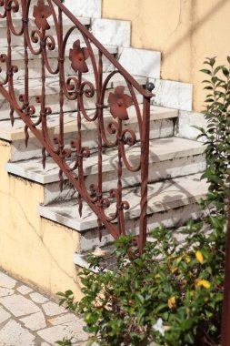 Eski paslı demir parmaklıklar ve İtalyan evinin girişindeki mermer merdivenler. Açık hava tasarımı ve güneş ışığı. İşlenmiş demir ve mermer arasındaki mimari kontrast. Yüksek kalite fotoğraf