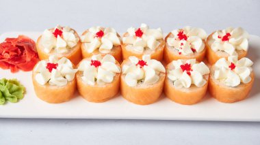 Gourmet somon suşi ruloları siyah bir tabakta garnitürlerle servis edilir, güzel bir yemek deneyimi için hazırdır. Yüksek kalite fotoğraf