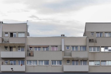 Balkonları ve pencereleri olan yeni, modern bir apartmanın ön cephesi.