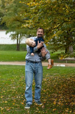 Genç baba ve oğlu sonbahar parkında. Mutlu aile kavramı..
