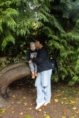 Genç anne ve küçük oğlu sonbahar parkında eğleniyorlar..