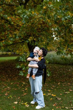 Genç anne ve küçük oğlu sonbahar parkında eğleniyorlar..