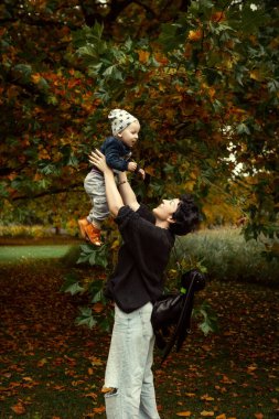 Genç anne ve küçük oğlu sonbahar parkında eğleniyorlar..