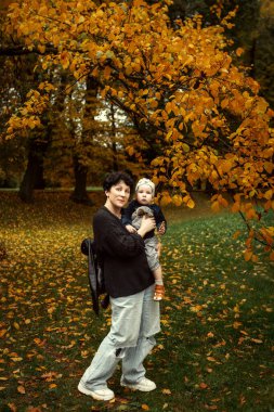 Genç anne ve küçük oğlu sonbahar parkında eğleniyorlar..