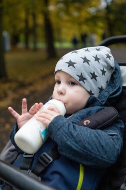 Parktaki şişeden süt içen tatlı küçük çocuk..