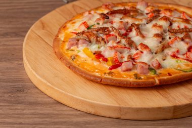 Tahta servis tahtasında nefis görünümlü böcek pizzası. Erimiş peynir, jambon, sosis, bambu kurdu, pupa, ipek böceği gibi canlı renklerle kaplıdır. Yakın plan.