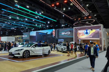 Nonthaburi, Tayland - 30 Kasım 2024: Bangkok Motor Show 'da çeşitli insanlar tarafından çevrelenmiş çeşitli elektrikli ve gelişmiş araçlarla dolu BYD kabini büyük kapalı sergi alanı.