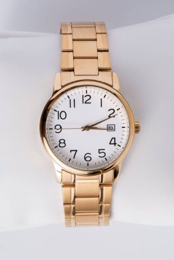 Beyaz arka planda altın tonlu metalden yapılmış lüks kol saati, geniş bir alan derinliği var..