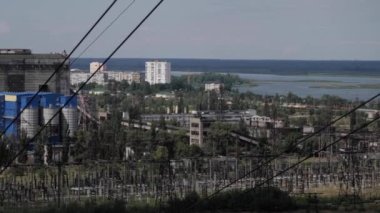 Ufuk boyunca uzanan bir elektrik iletim hattının heybetli varlığı. Yüksek metal yapılar elektrik enerjisiyle vızıldayan yüksek voltajlı kabloları destekler. Arka planda, bir güç
