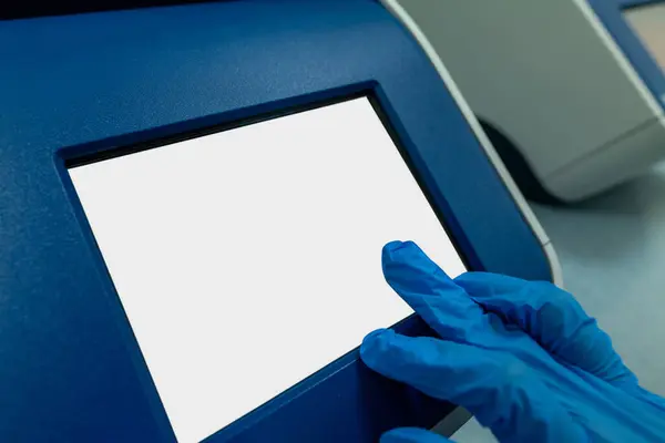 Doktor dokunmatik ekrandaki hasta verilerini inceliyor. Kaliteli fotoğraf, dokunmatik ekran monitörü kullanan eldivenli birinin yakın çekimini gösteriyor. Monitörde tıbbi veriler var.