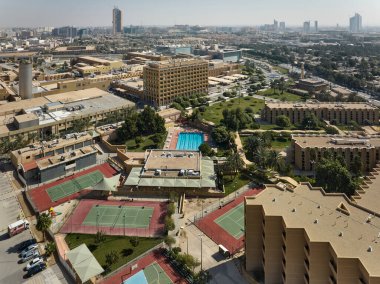City Swimming Pool and Tennis Courts from Above. High quality photoThis aerial photograph captures a city rooftop recreation complex, featuring a swimming pool and several tennis courts. The clipart