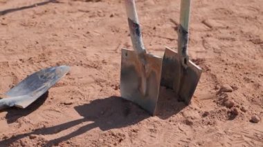 Bir bahçe aleti, bir kürek, gevşek bir toprak yığınının tepesinde dinleniyor. Kürek sapı tahtadan yapılmıştır ve kahverengi renkte görünür, metal kürek kafa ise serin, gri bir tondur. Gevşek toprak yığını