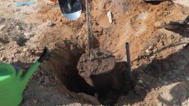 Genç bir ağacın dikildiği bir toprak yığınının etrafında bir grup insan duruyor. Ön planda takım elbiseli ve kravatlı bir adam bir küreğe yaslanıyor. Arkasında, iş kıyafeti giymiş bir kadın vardı.